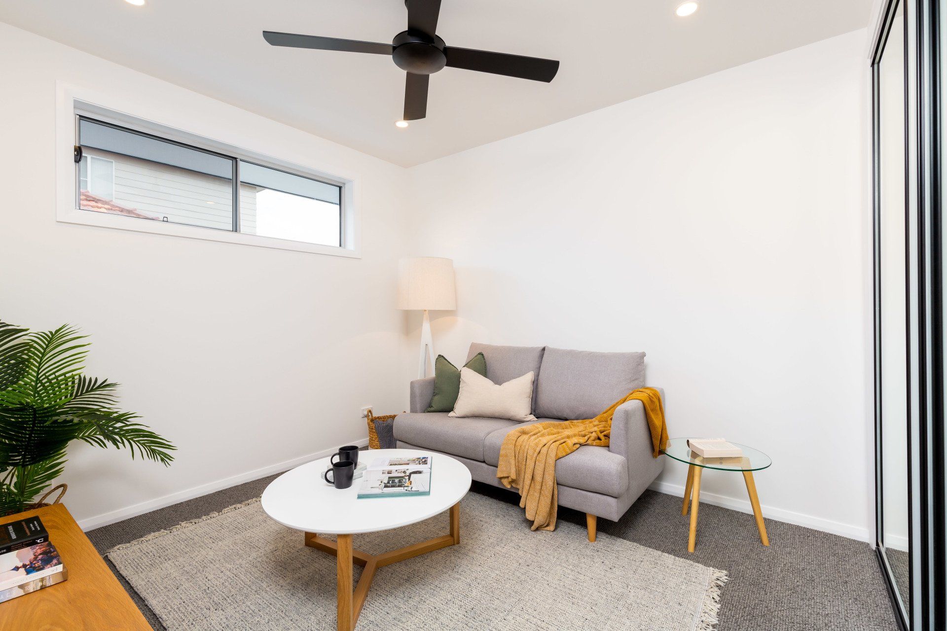 Cozy, modern living room with gray sofa, round coffee table, rug, and ceiling fan.