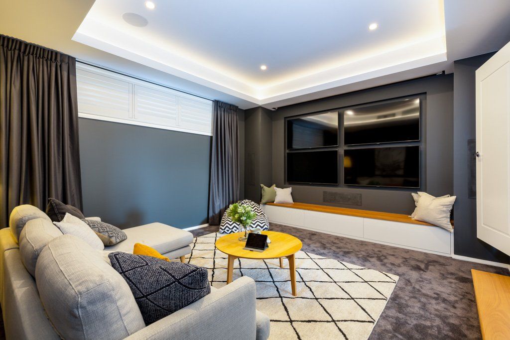 Cozy living room with gray walls, sofa, and TV, with a yellow coffee table on a geometric rug.