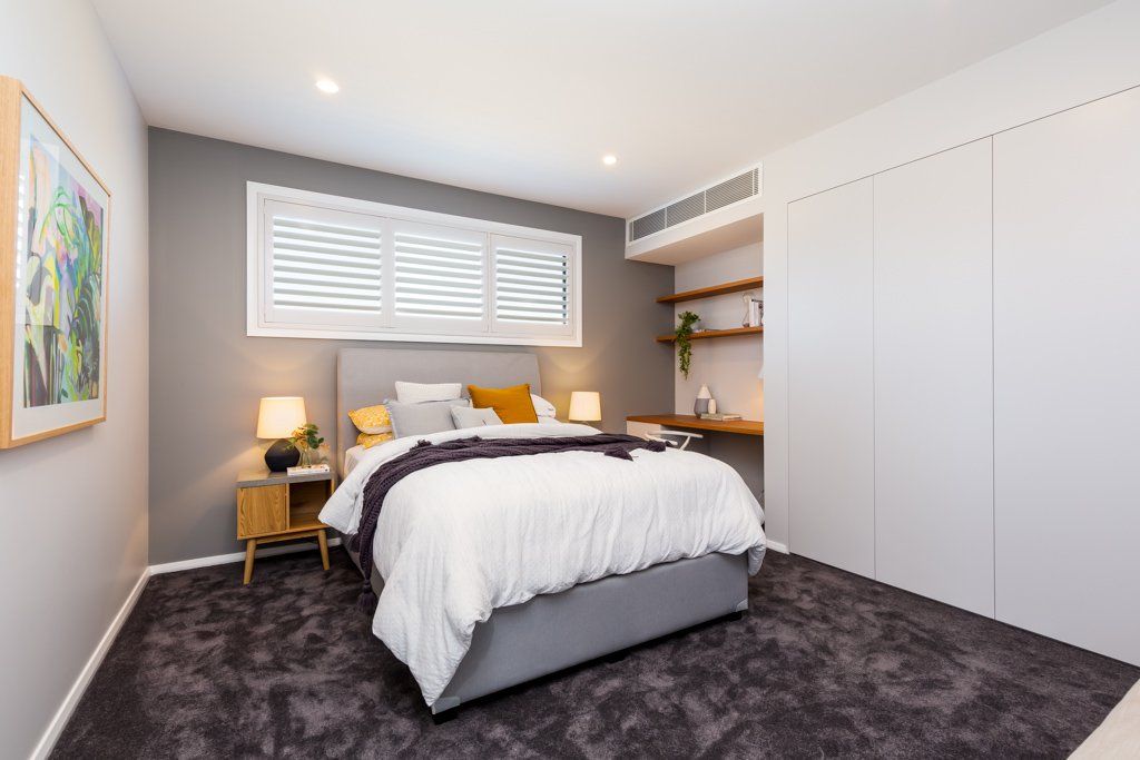 Bedroom with gray walls, bed, nightstands, and large white closet. Dark gray carpet.