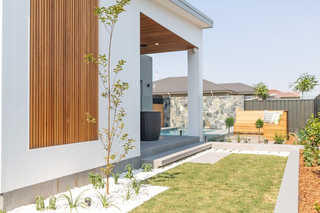 Modern home exterior with wood paneling, a lawn, and landscaped yard.