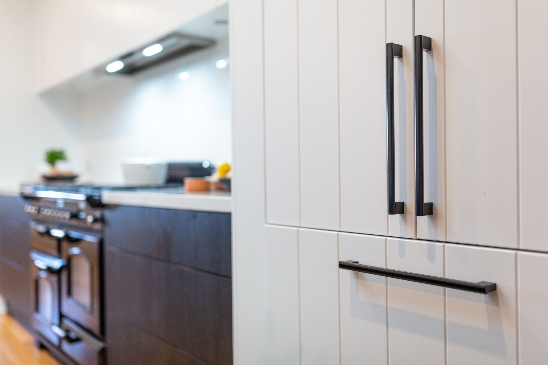 White and dark wood kitchen with black cabinet pulls, focus on cabinetry.
