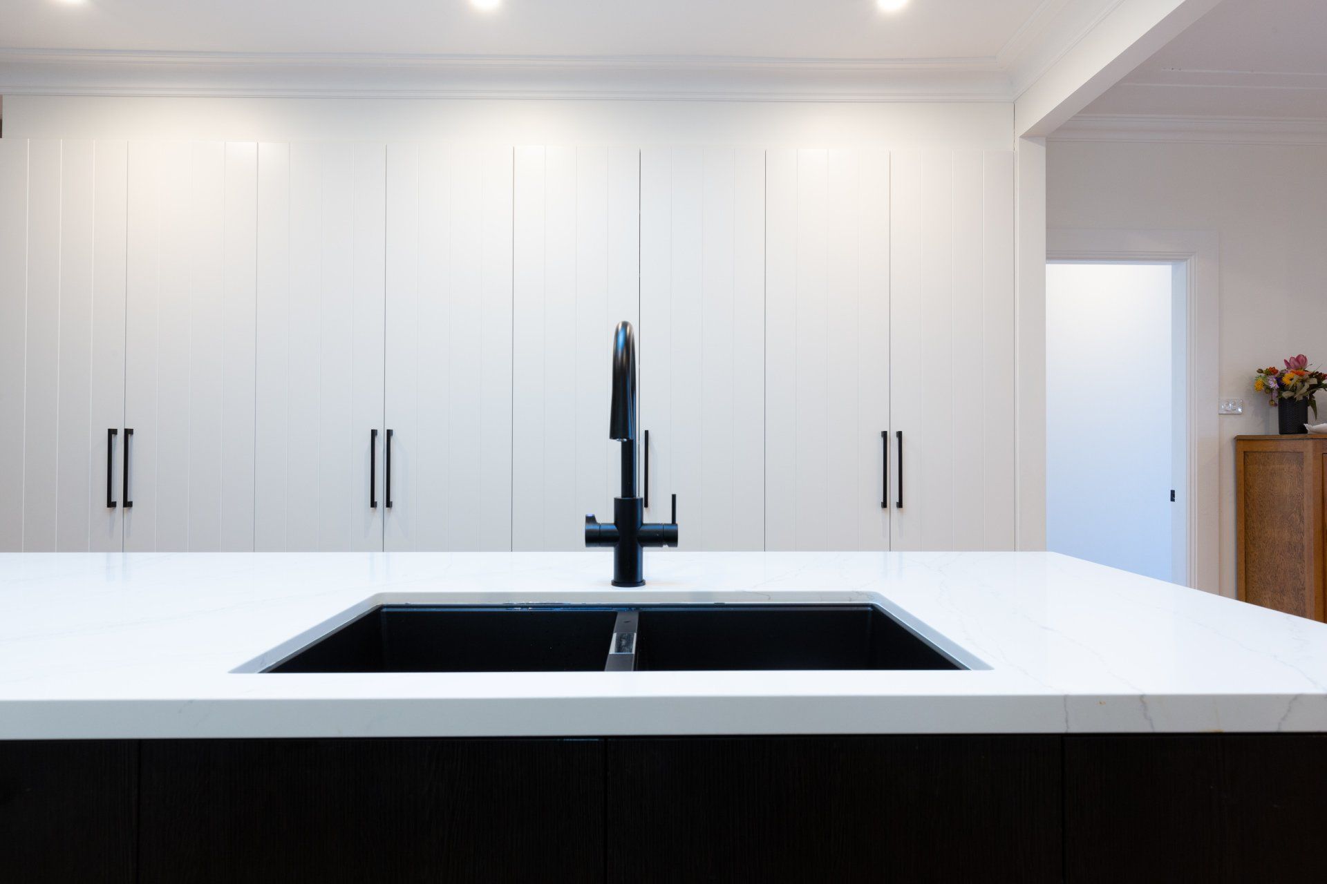 Modern kitchen with a white countertop, black sink, and white cabinets.