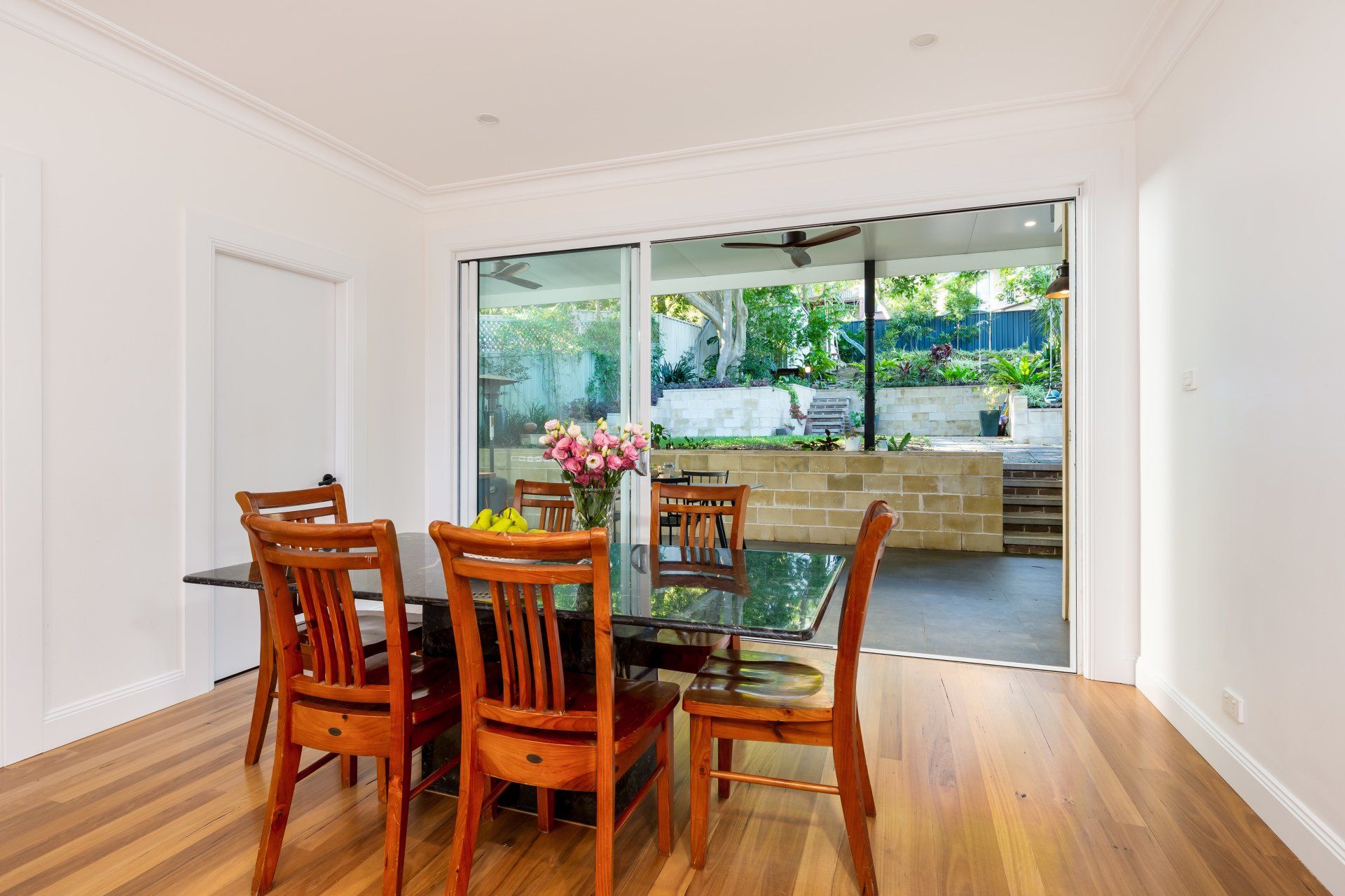 Dining room with wooden furniture, black table, sliding doors open to a patio.