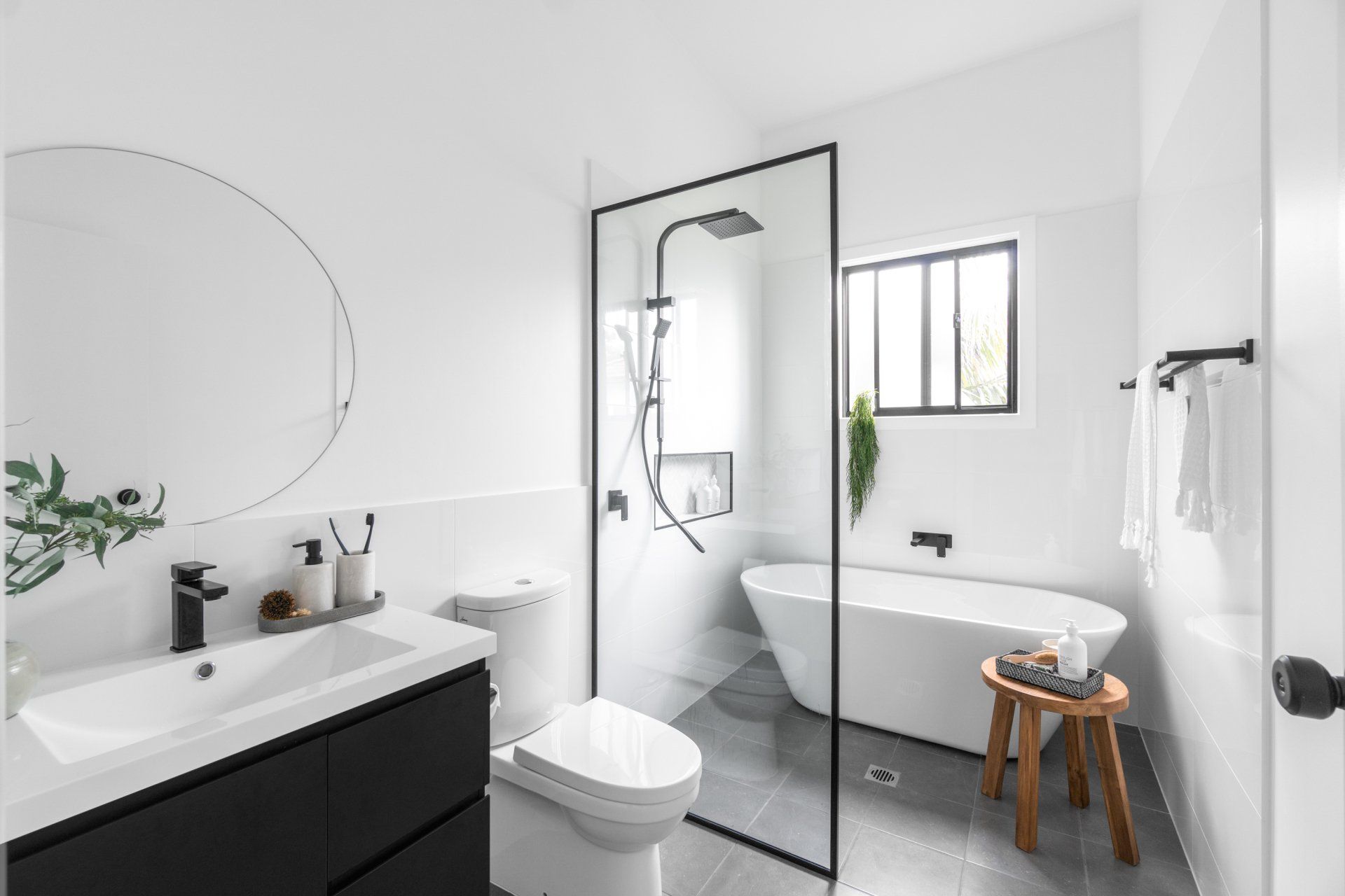 Modern white bathroom with black accents, shower, tub, and vanity.