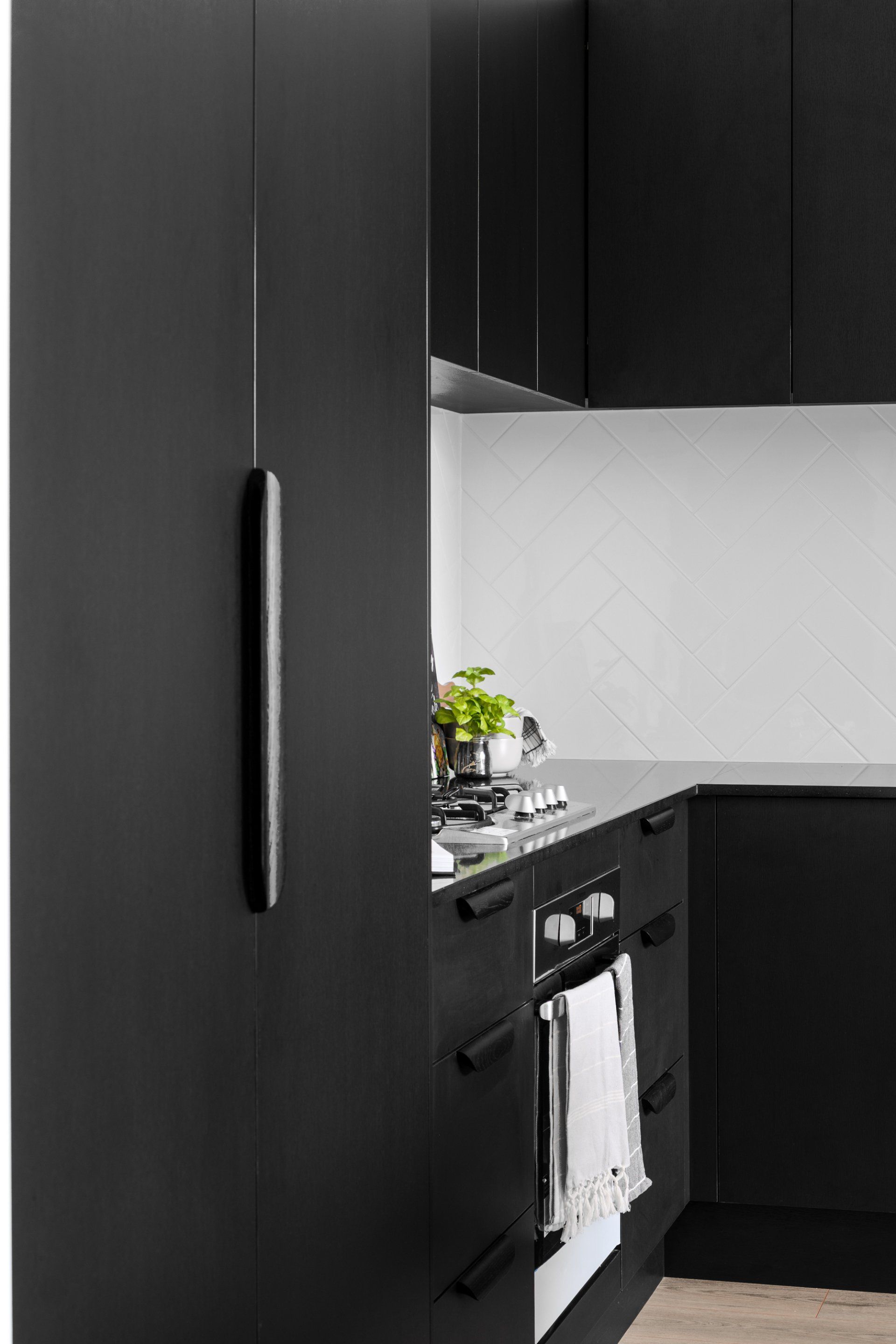 Black kitchen cabinets with a long, thin black handle on one.