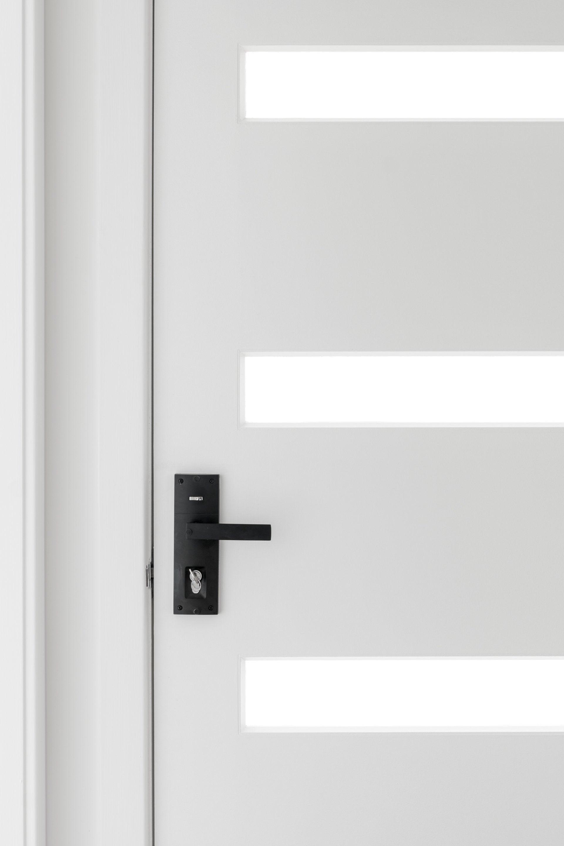 White door with three horizontal rectangular glass inserts; black door handle.