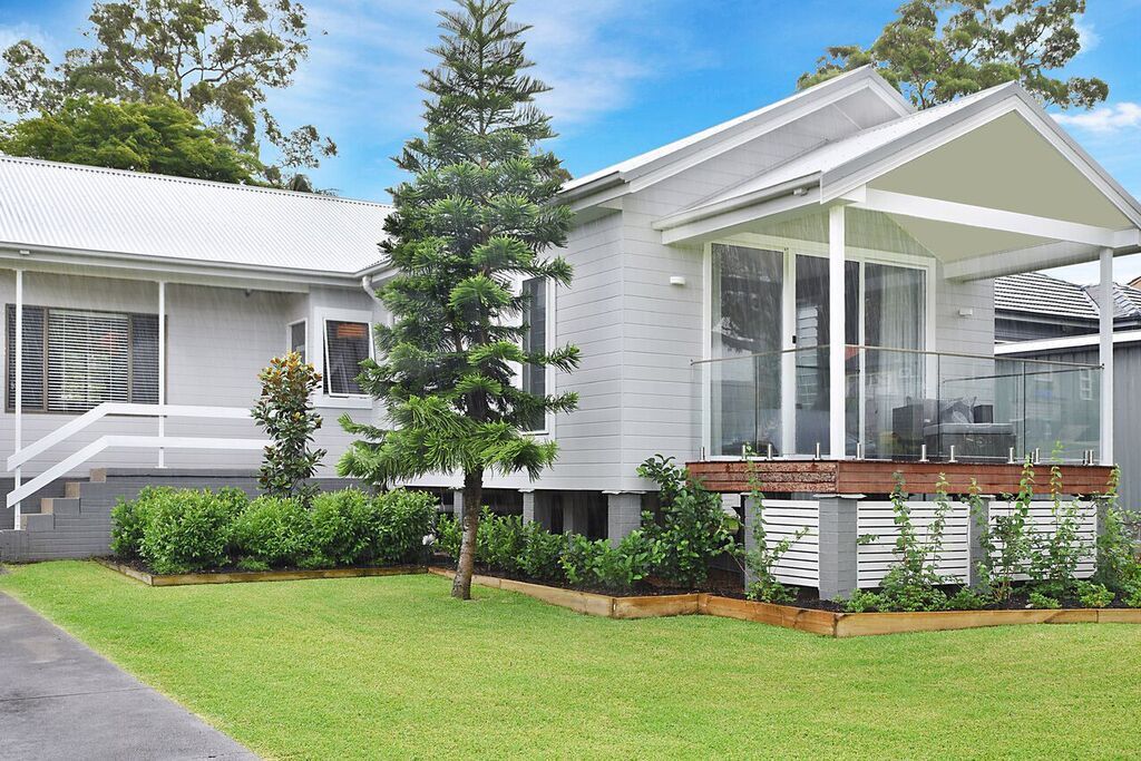 Gray brick house with porch and white trim; green lawn and landscaping.