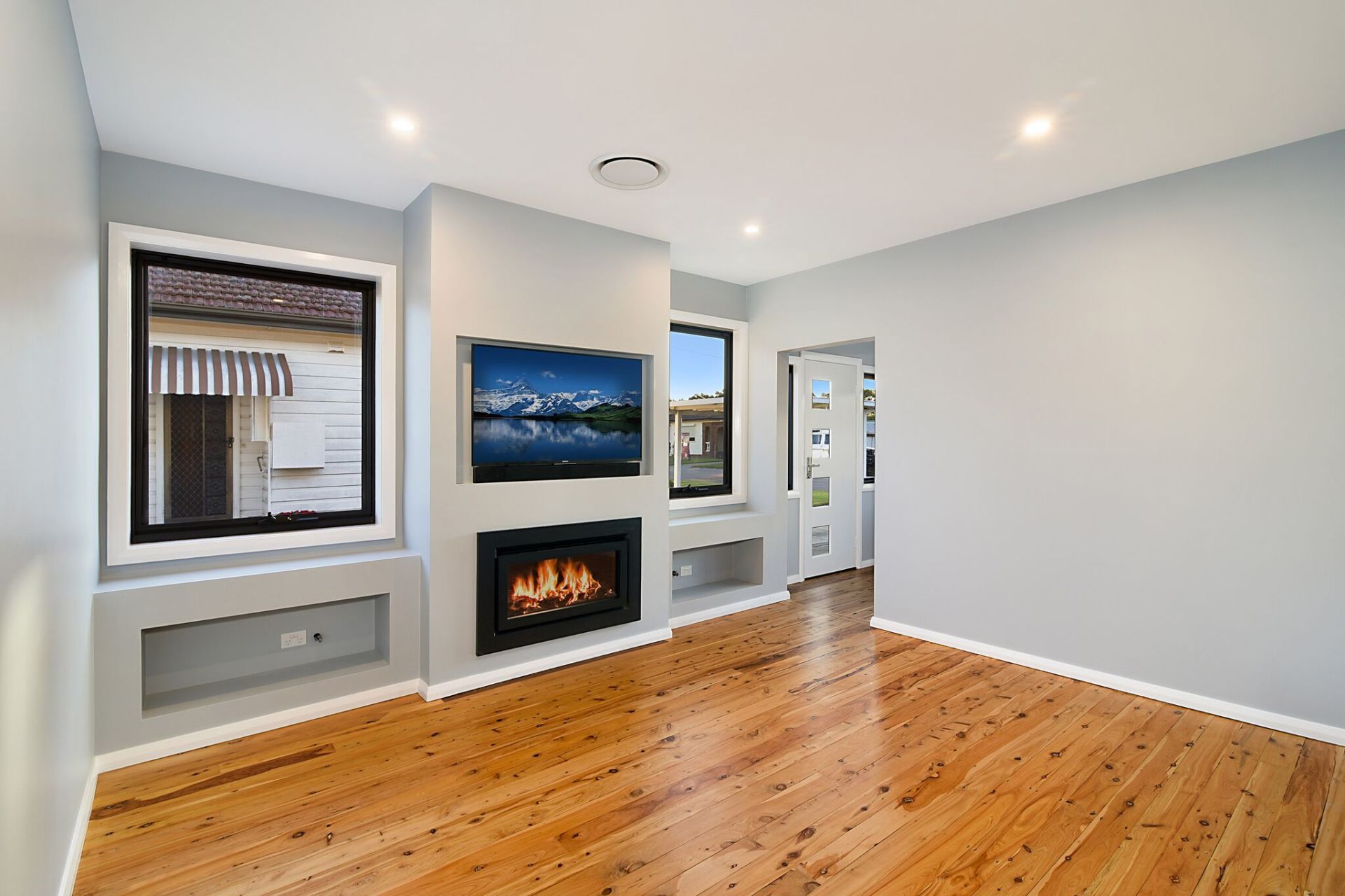 Living room with fireplace, TV, wood floor, and light blue walls.