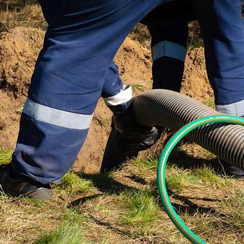Worker Holding Pipe and Cleaning Septic Tank — Delaware, OH — Wells Septic & Drain Cleaning Worker Holding Pipe and Cleaning Septic Tank — Delaware, OH — Wells Septic & Drain Cleaning