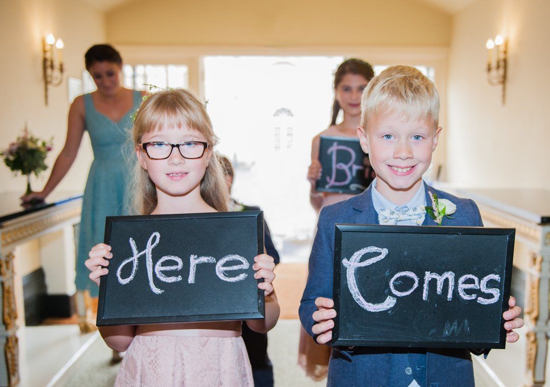 Bridesmaids and Pageboys holding small black chalkboards,