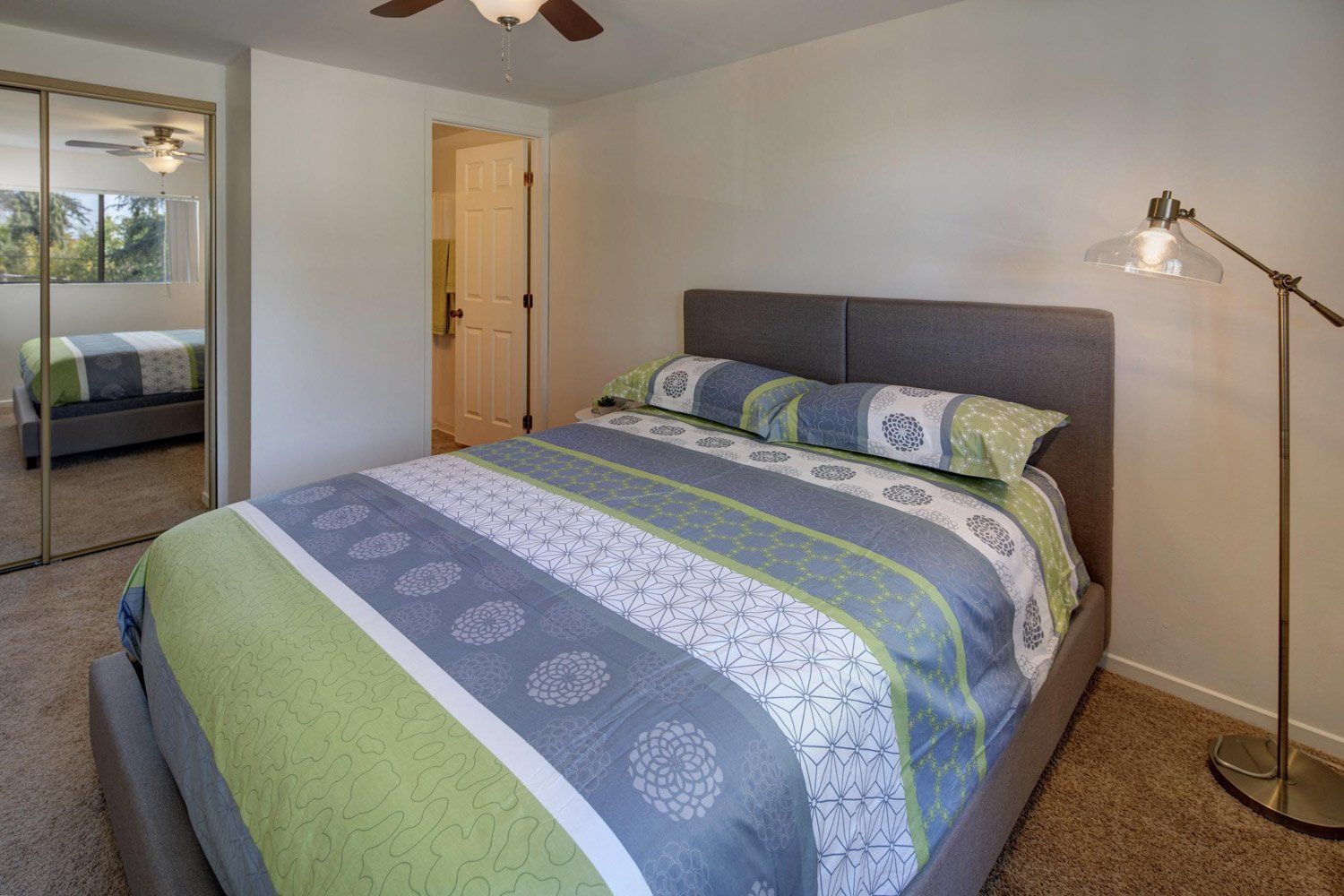 A bedroom with a king size bed and a lamp.