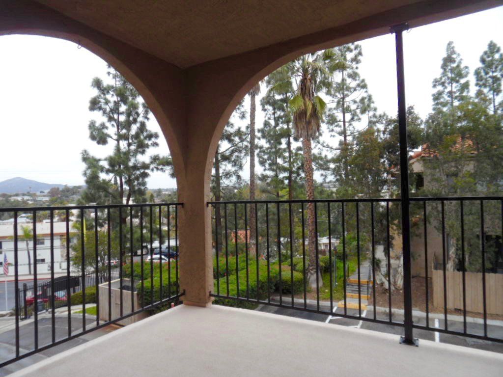 A balcony with a metal railing and trees in the background