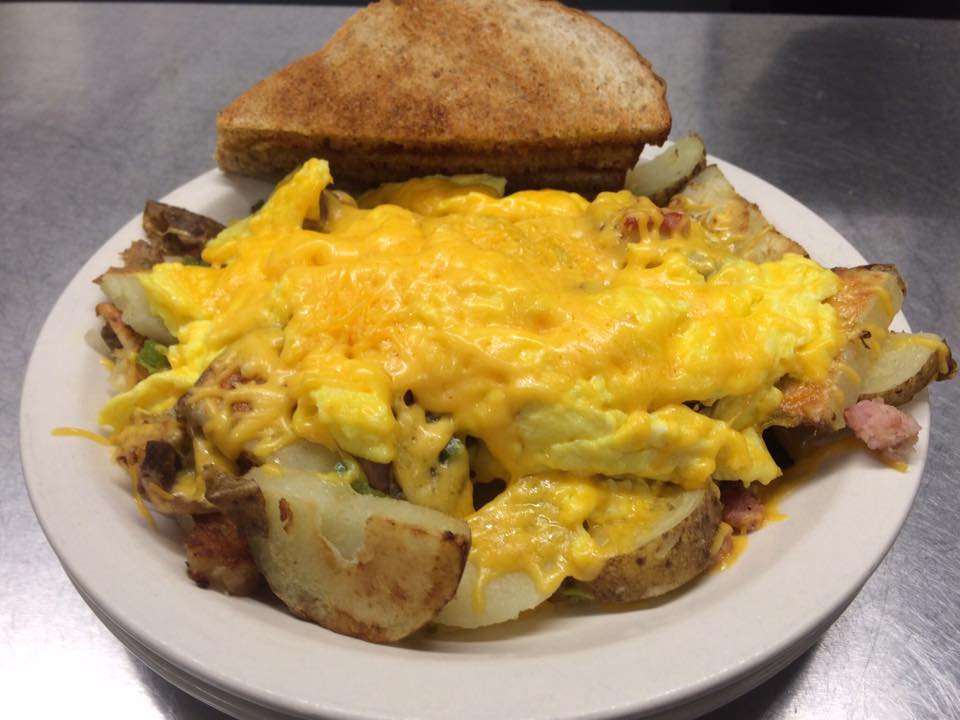 A plate of food with eggs potatoes and toast on a table.