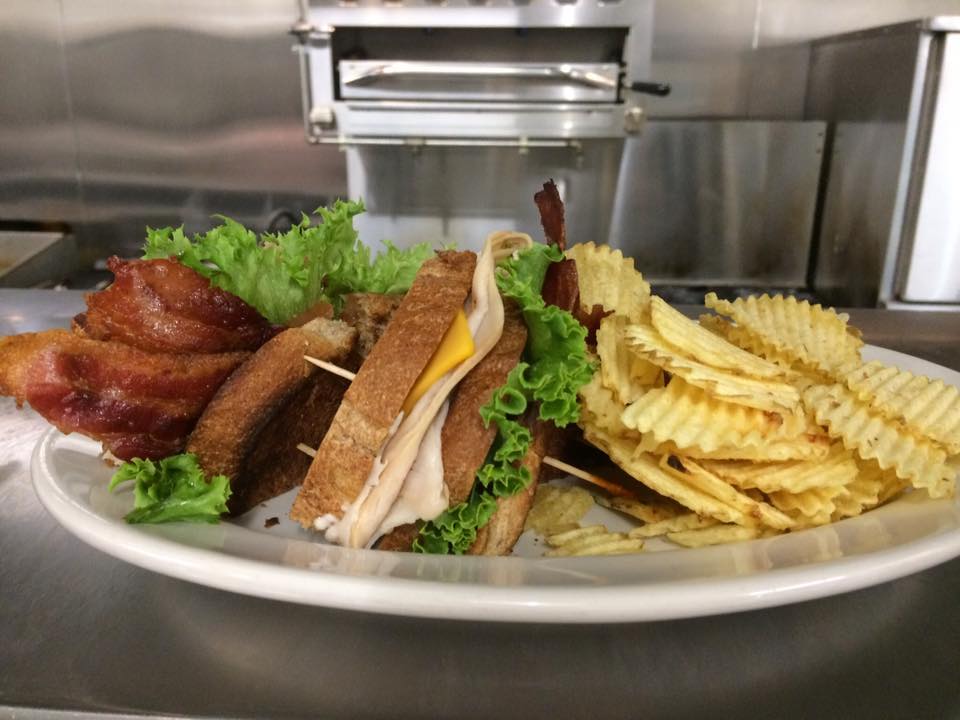 A white plate topped with a club sandwich and french fries