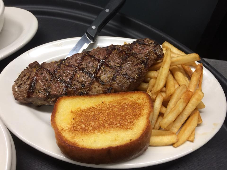 A white plate topped with a steak and french fries