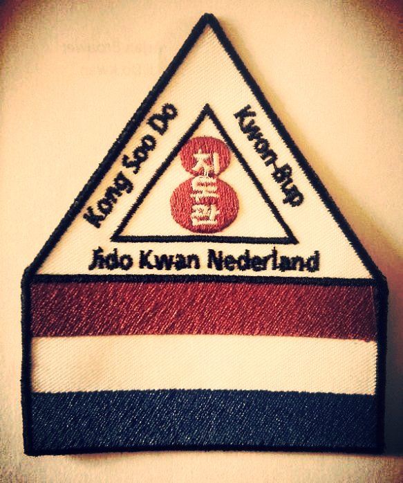 Een geborduurde driehoekige patch met de tekst 