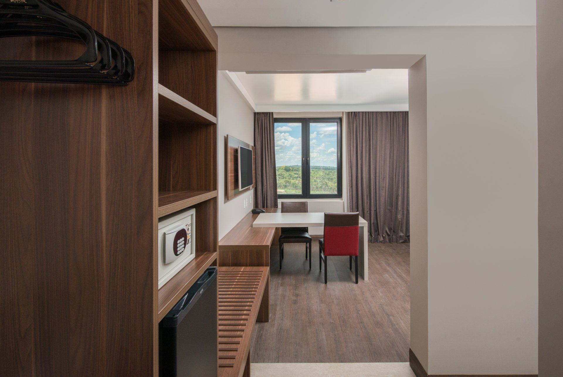 Quarto moderno com estantes de madeira, escrivaninha, cadeira e janela com cortinas.