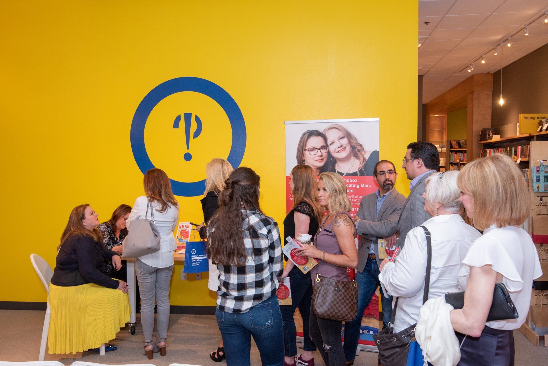 A group of people are standing in front of a yellow wall.