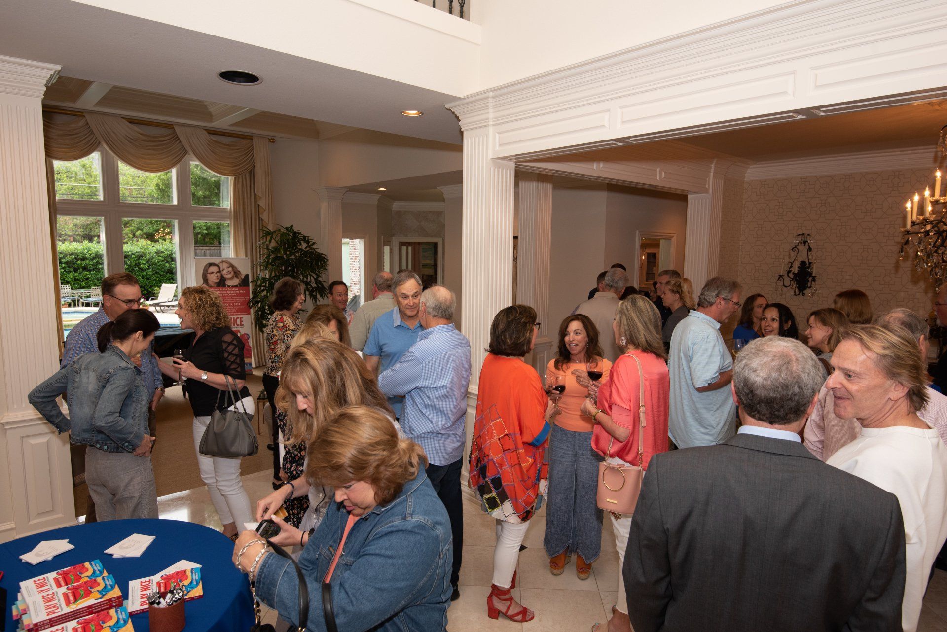 A group of people are standing in a room talking to each other.