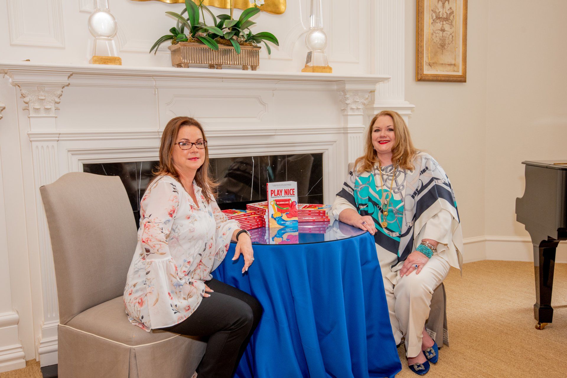Two women are sitting at a table with a blue table cloth.