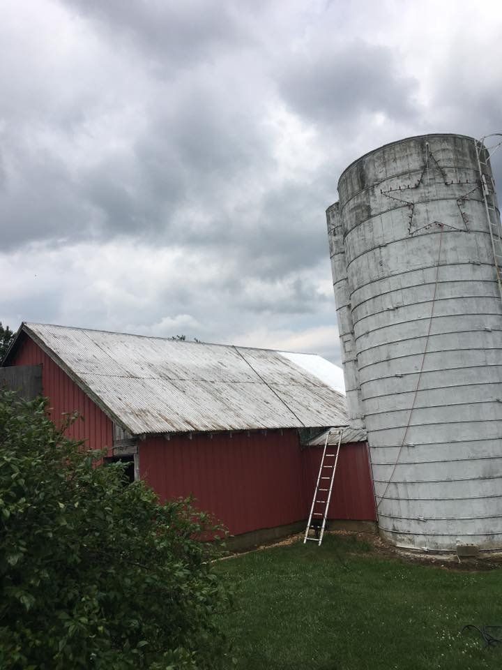 a red barn with a white silo in front of it .