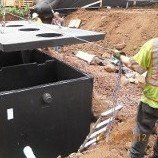 Gecko enterprises employee pulling rope from septic tank