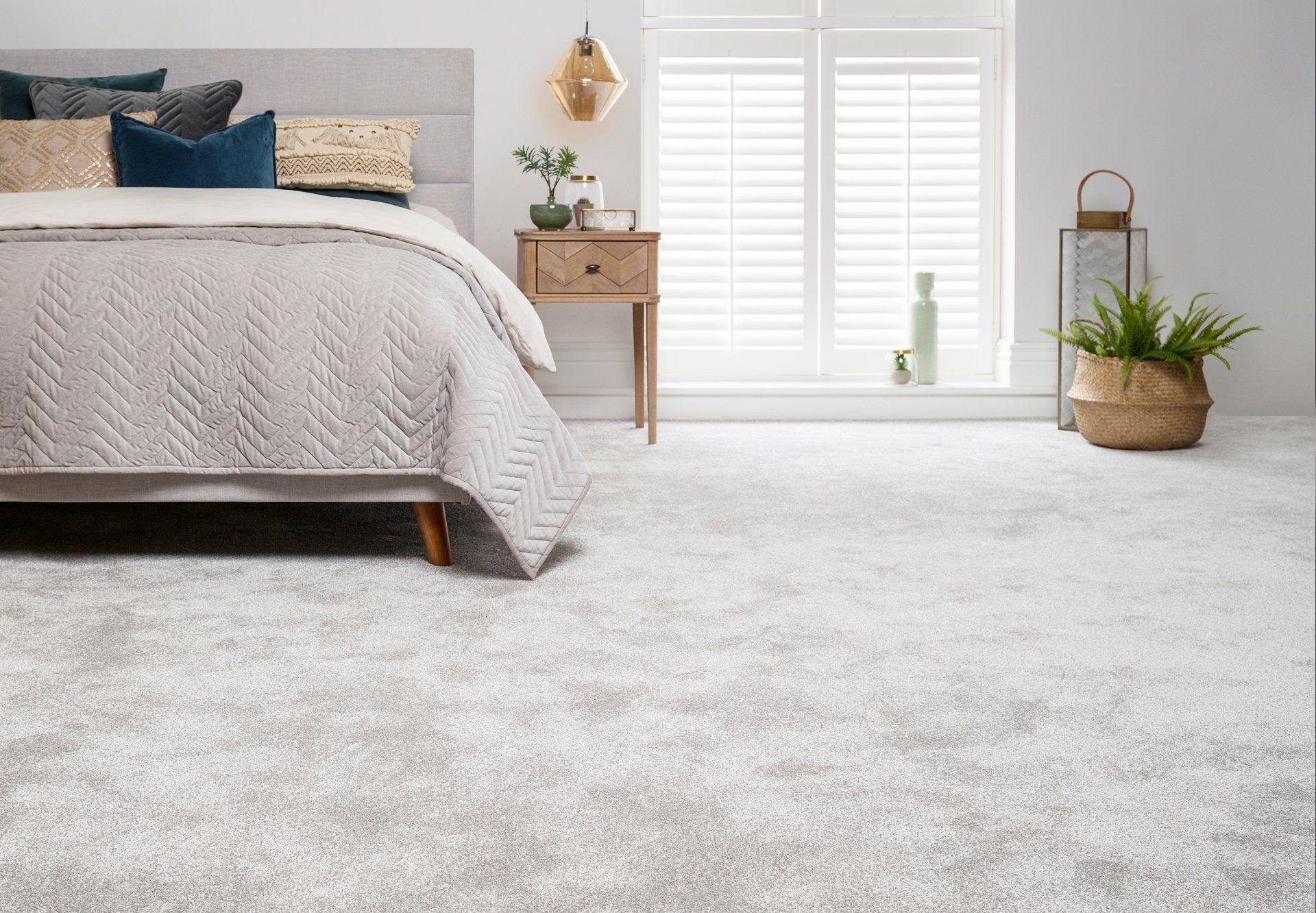 Newly fitted grey carpet in a large bedroom with a large bed and double back doors