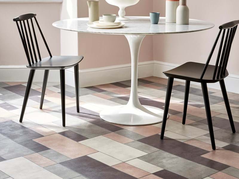 Patterned tiled flooring in a kitchen with a table and chairs in the background