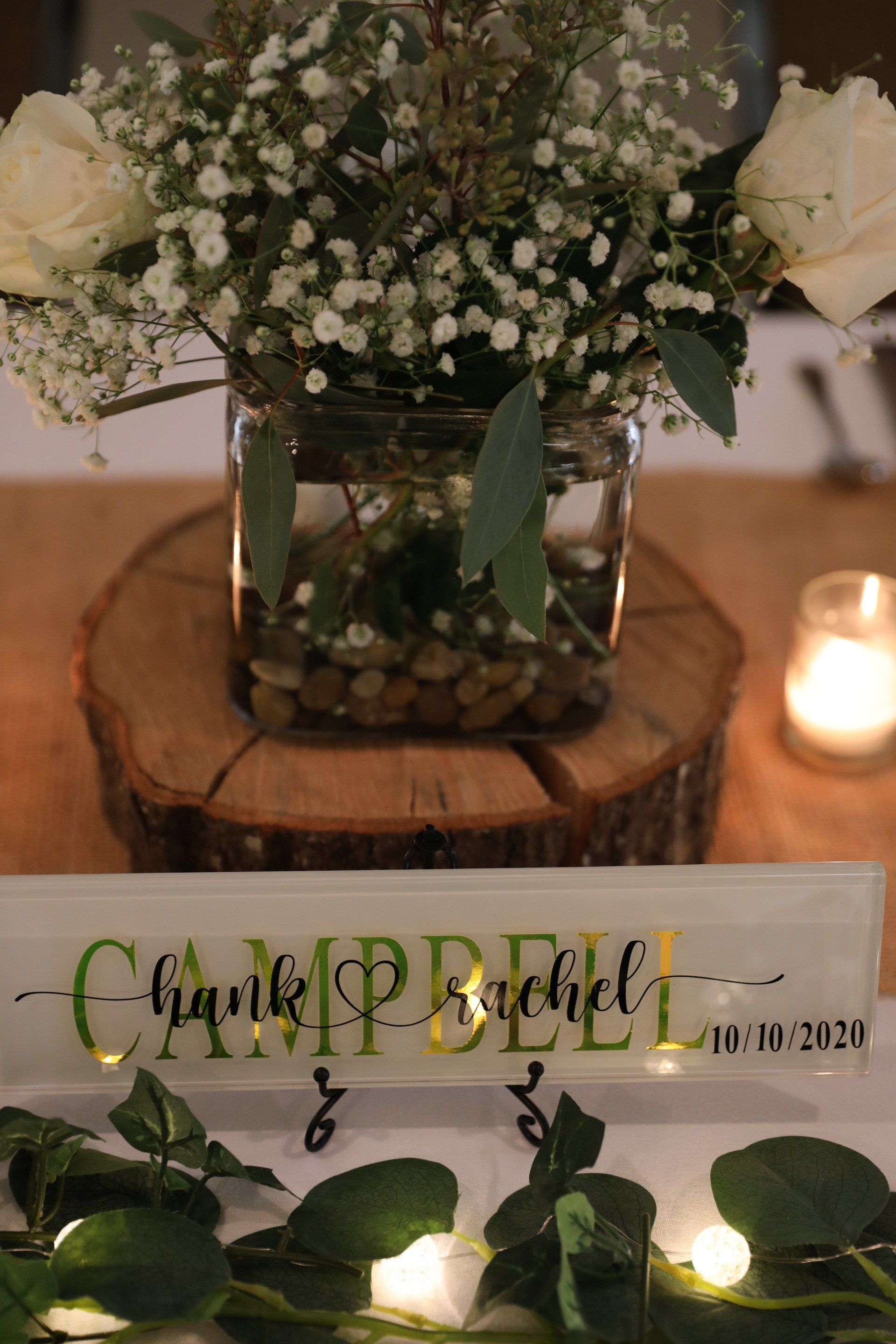 Wedding reception centerpiece with floral arrangement, table sign reading 