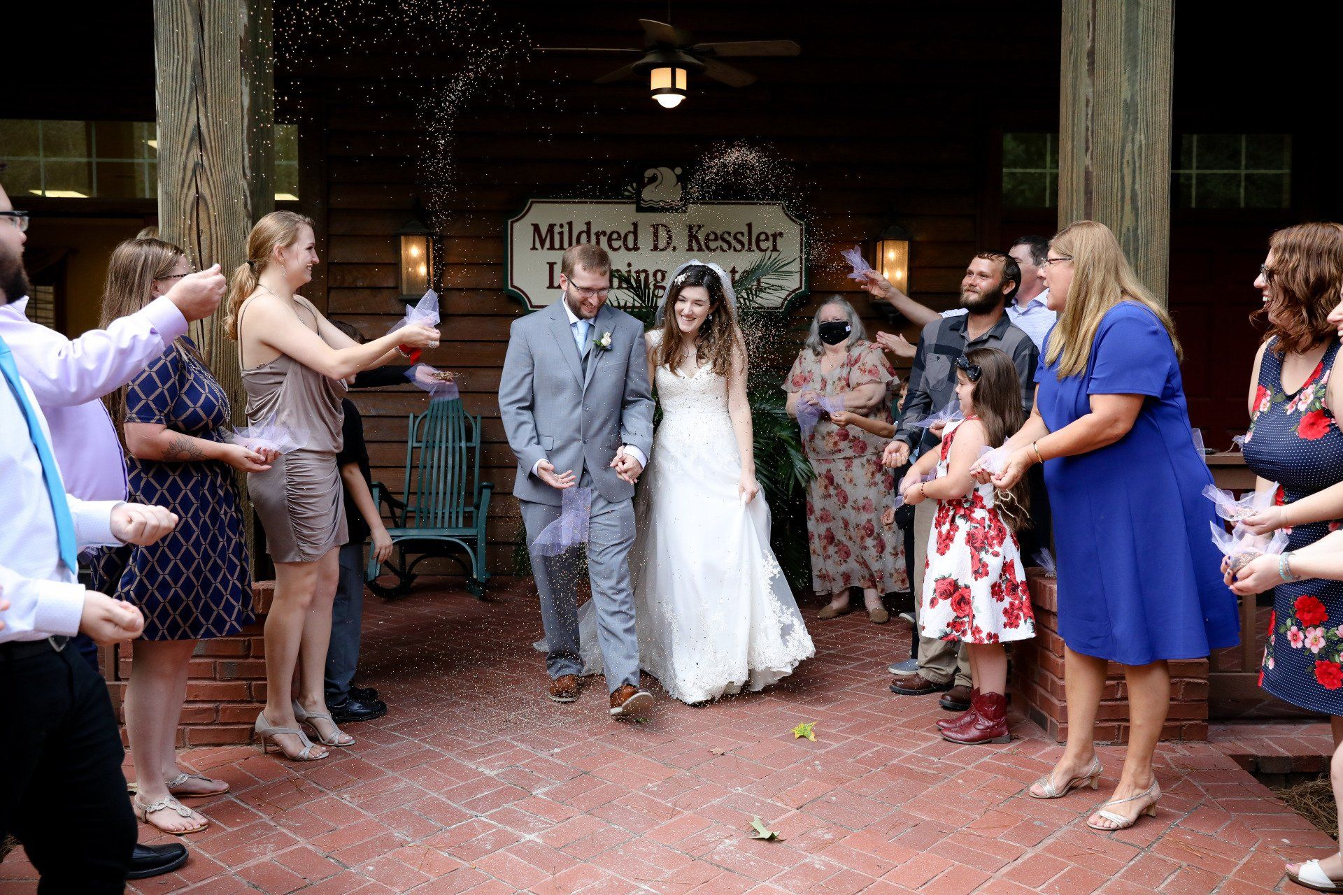 Newlyweds exiting a building, showered with confetti by wedding guests.