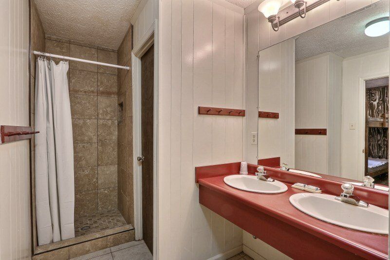 Bathroom with red countertop, two sinks, shower, and a large mirror.