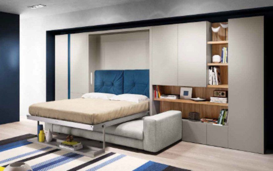 una sala con un divano angolare di color grigio e un mobile in legno con dei libri