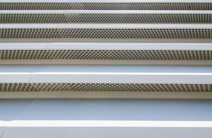 Close-up of a vented metal grille with horizontal silver and beige slats