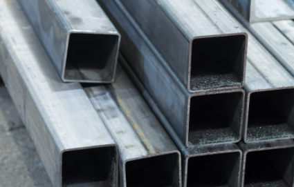 Stacked silver metal square tubes on a industrial surface