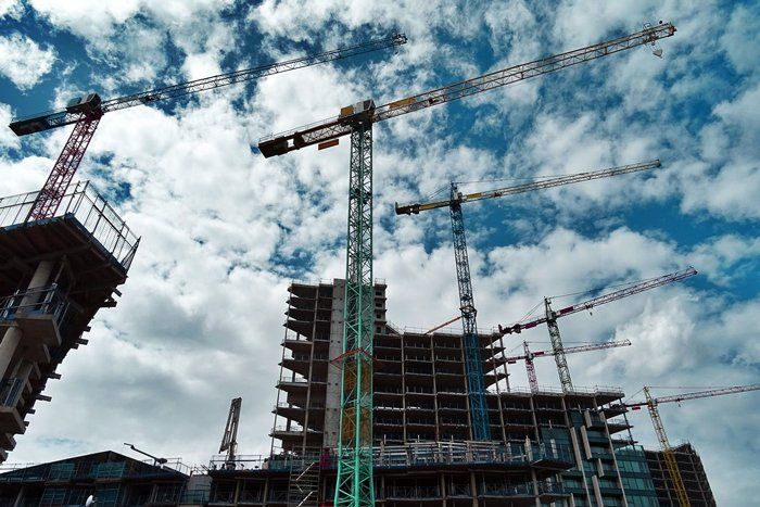 A building is being built with cranes and a blue sky in the background.