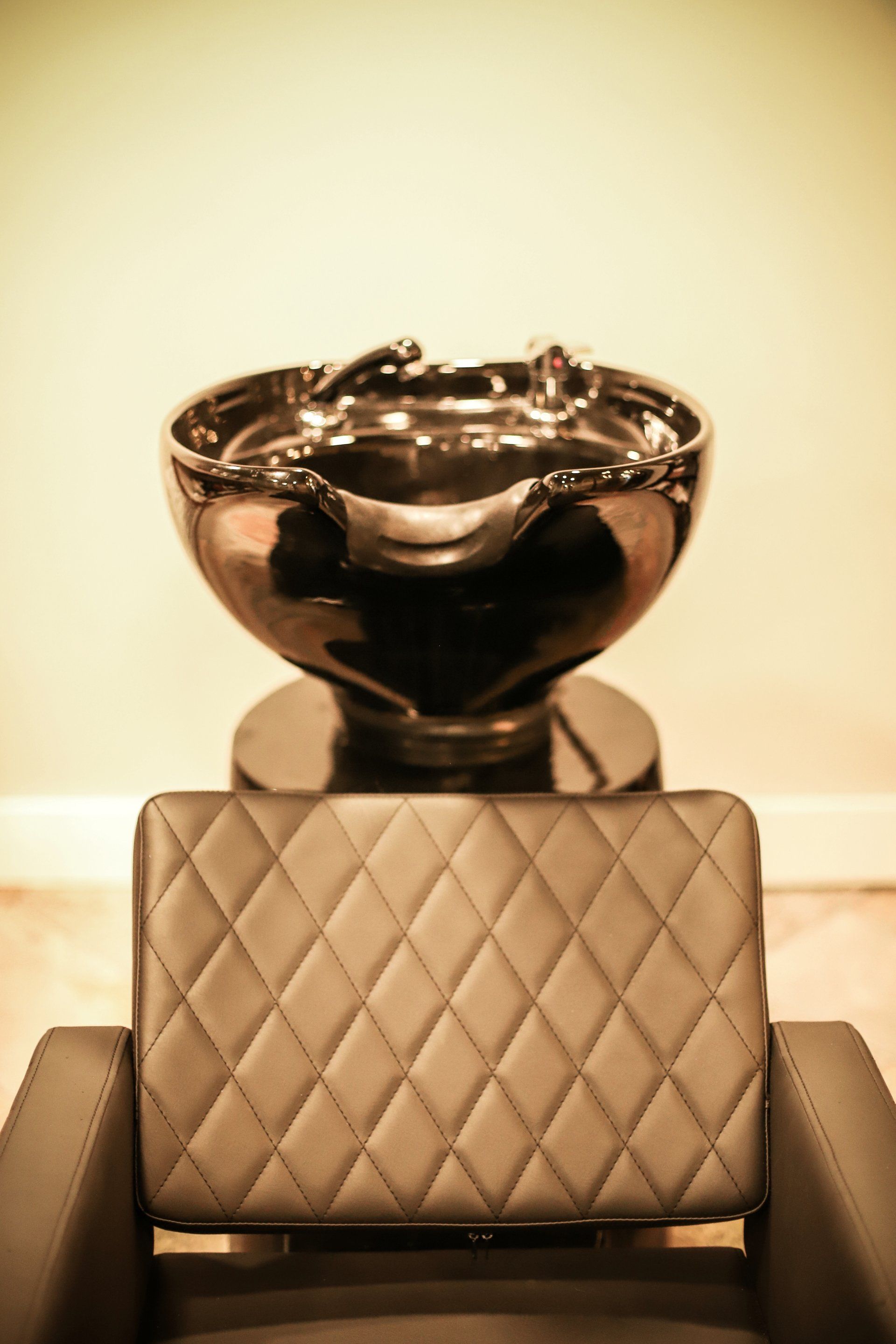 Hair-washing sink over a quilted salon chair in a softly lit room