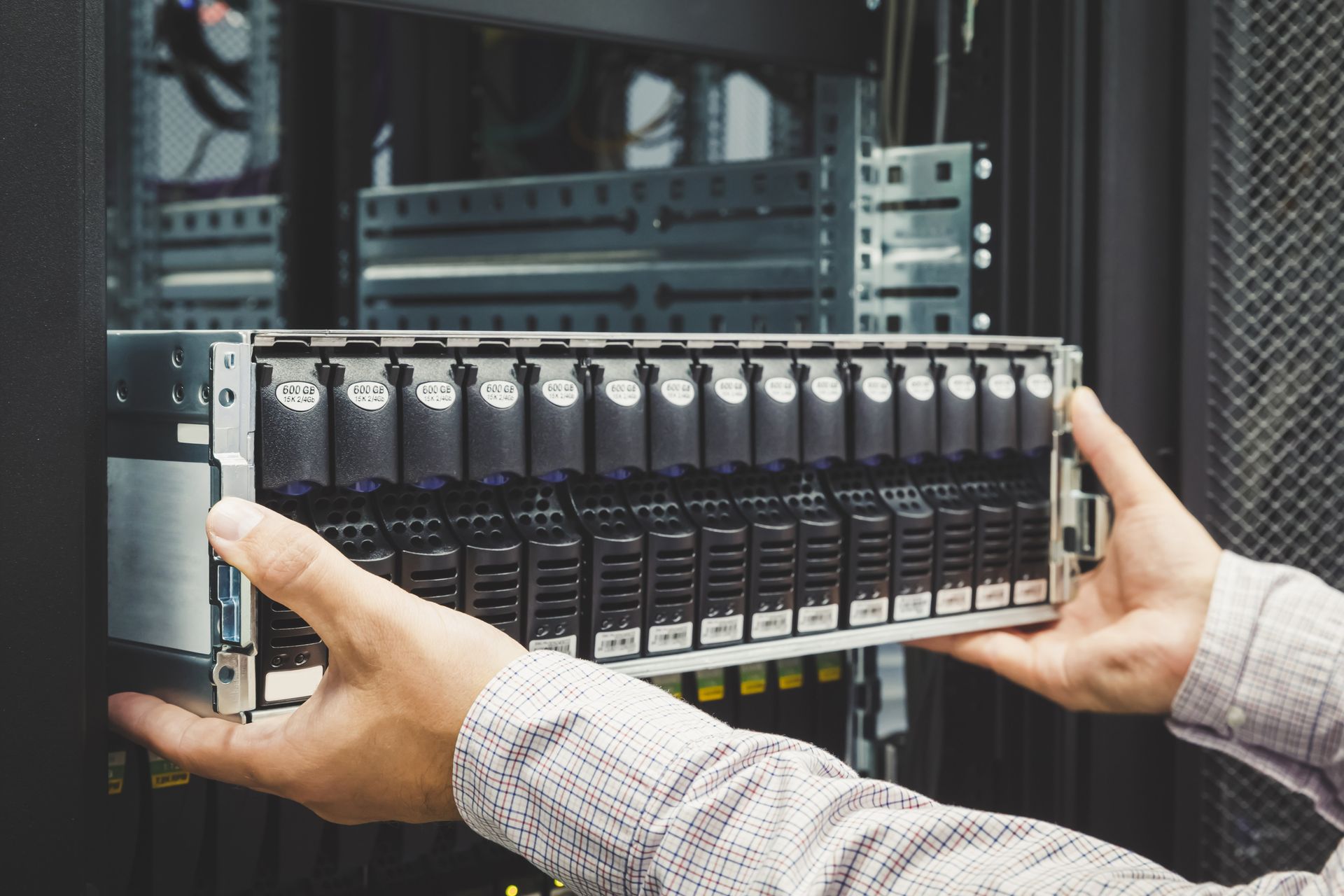 Hände halten eine Server-Speichereinheit und bereiten deren Installation in einem Rack in einem Rechenzentrum vor.
