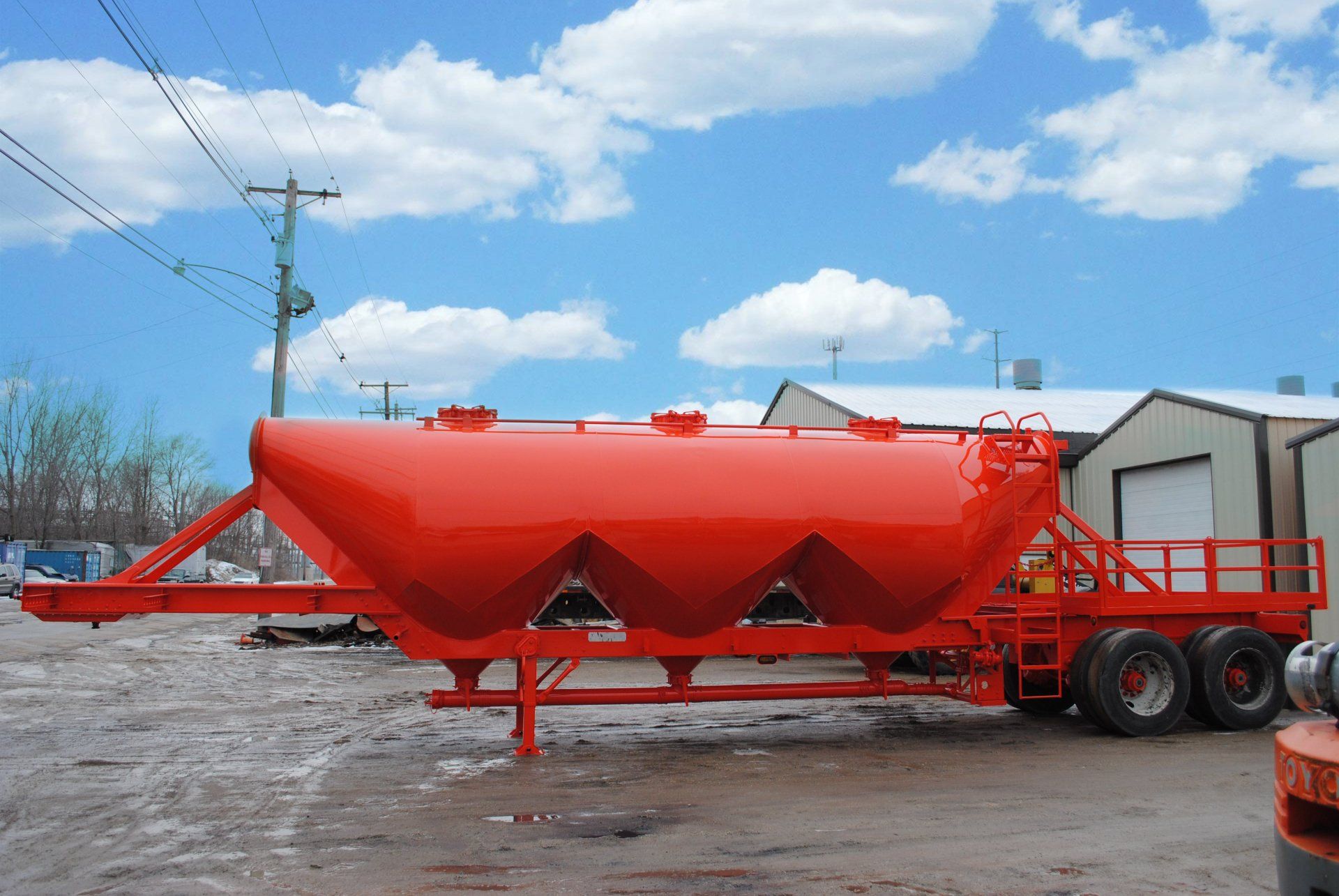 A large red trailer is parked in front of a building