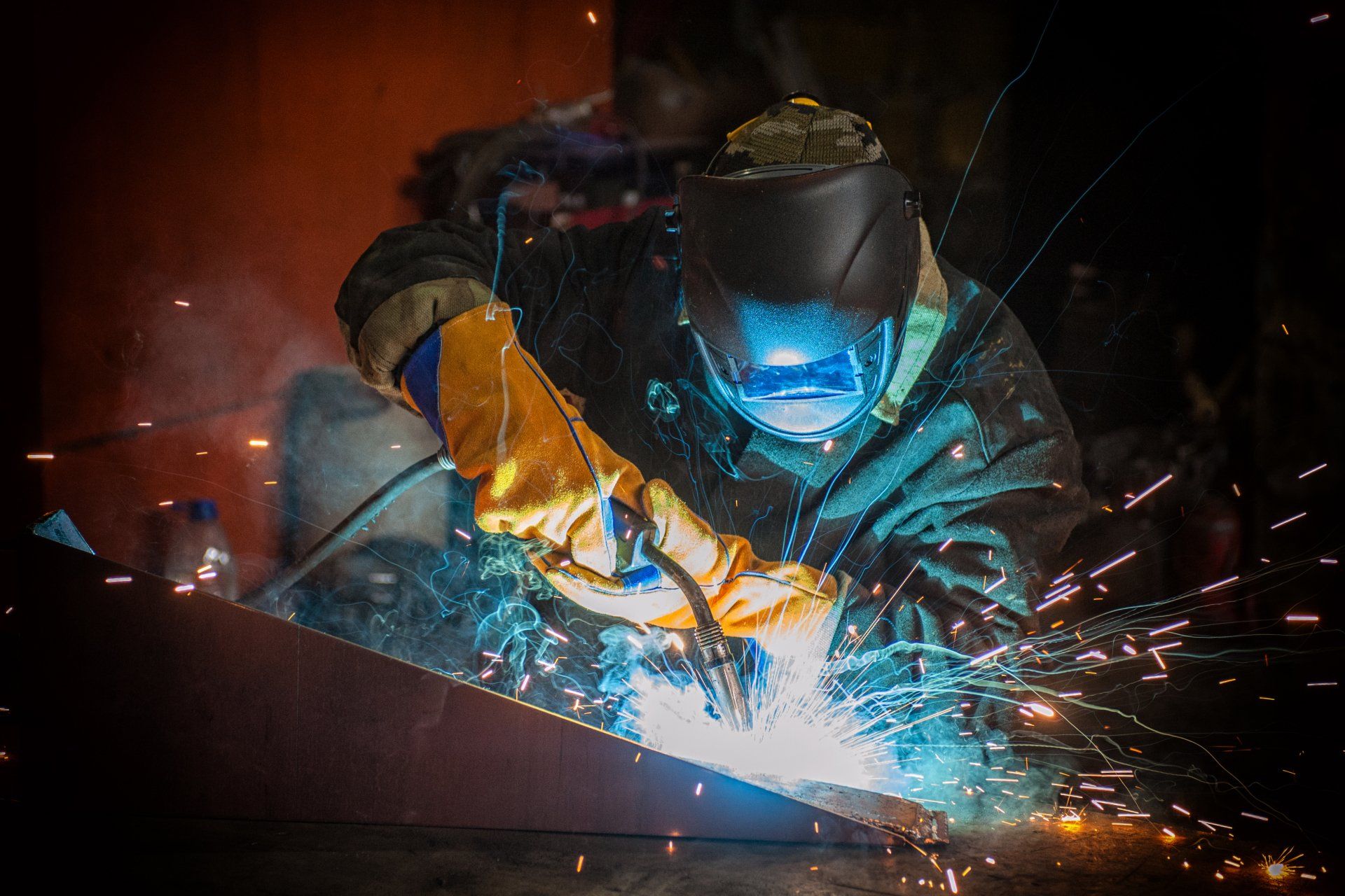 A man is welding a piece of metal in a factory.