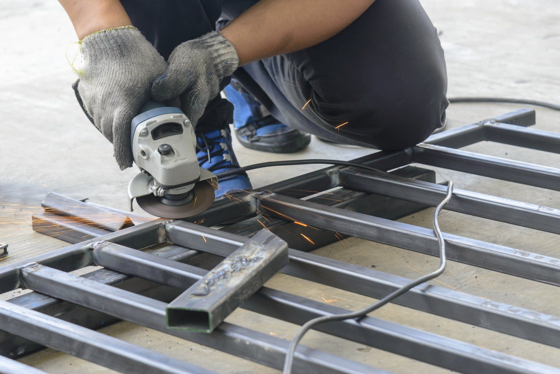 A man is grinding a piece of metal with a grinder.