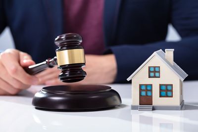 Hand Striking Gavel Near House Model — Winter Haven, FL — Straughn & Turner, P.A.