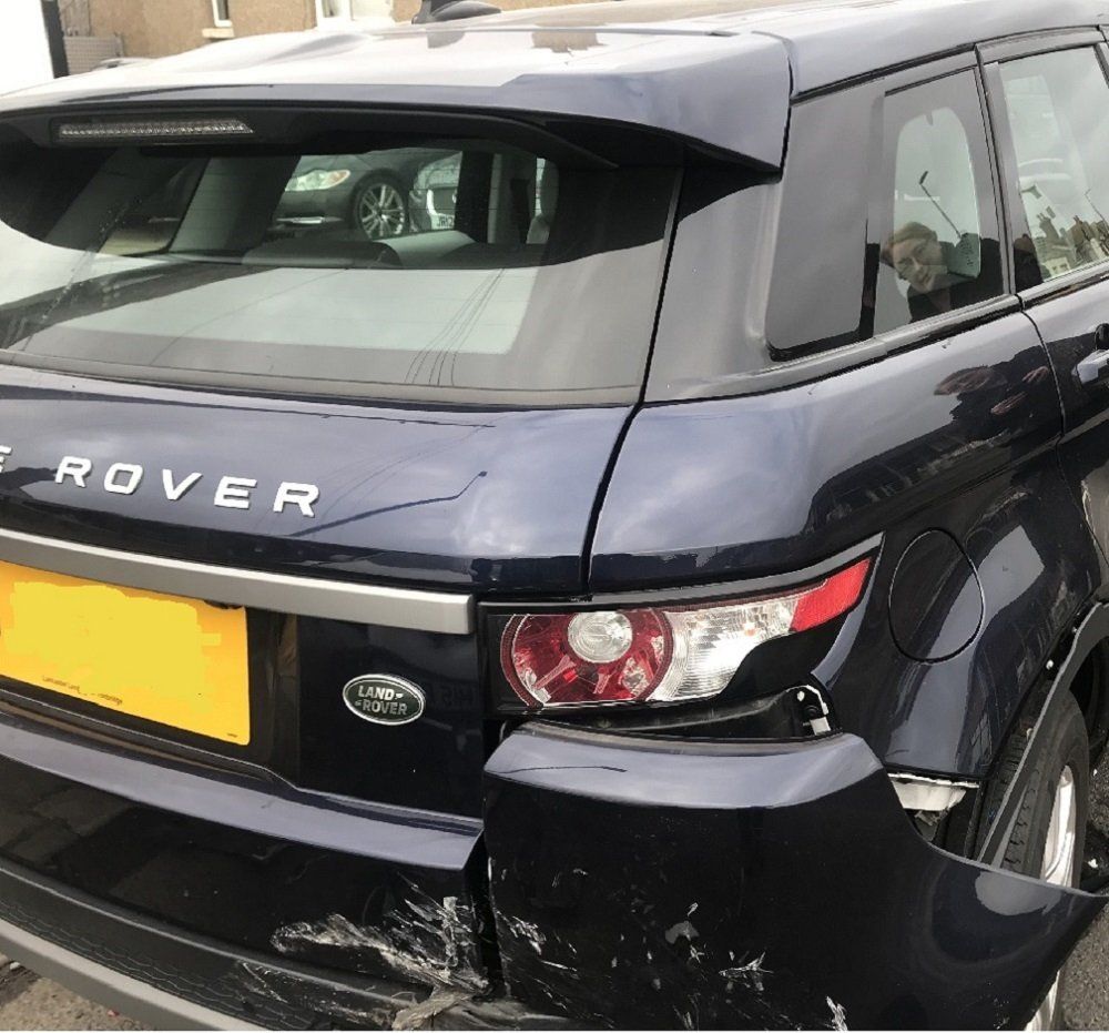 Damaged blue Range Rover rear bumper and taillight. Visible