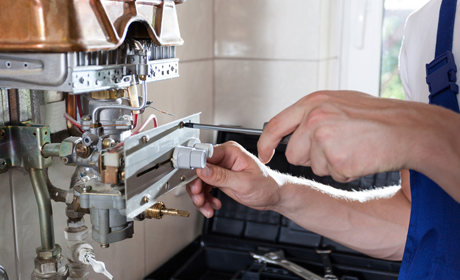 an electrician checking and testing the boiler with a tool