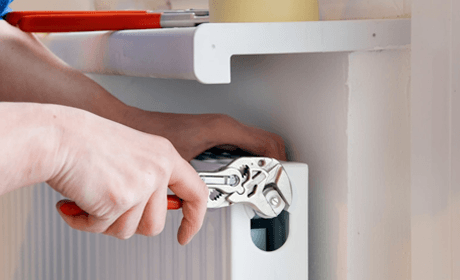 a person using pliers to repair the central heating system