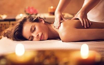 Donna che riceve un massaggio alla schiena in una spa con candele e fiori.