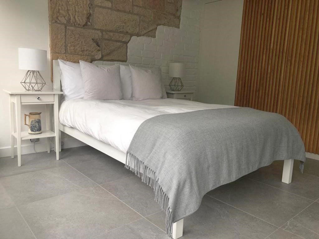 A bedroom with a bed , nightstand , and lamp.
