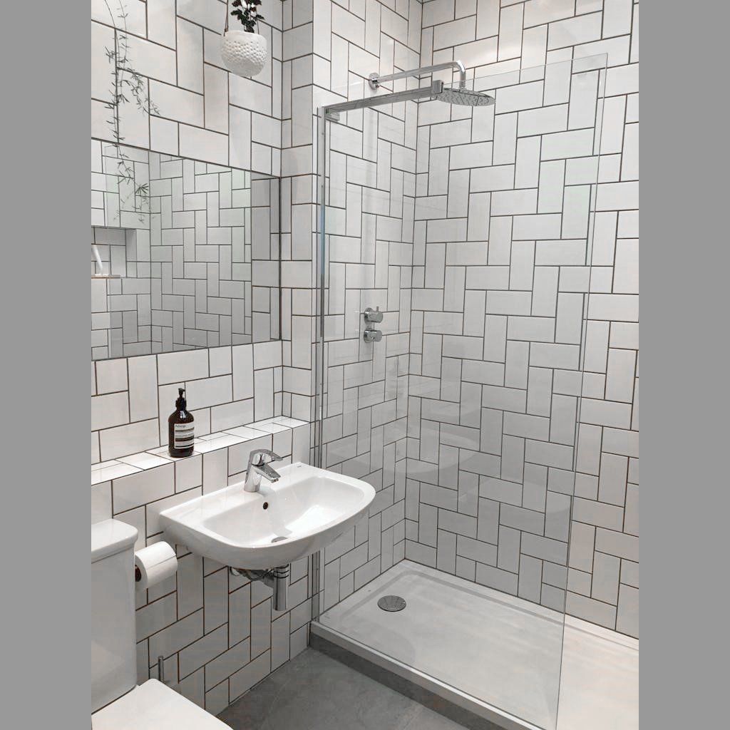 A bathroom with white tiles and a walk in shower