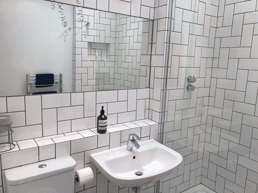 A bathroom with white tiles and a sink and toilet