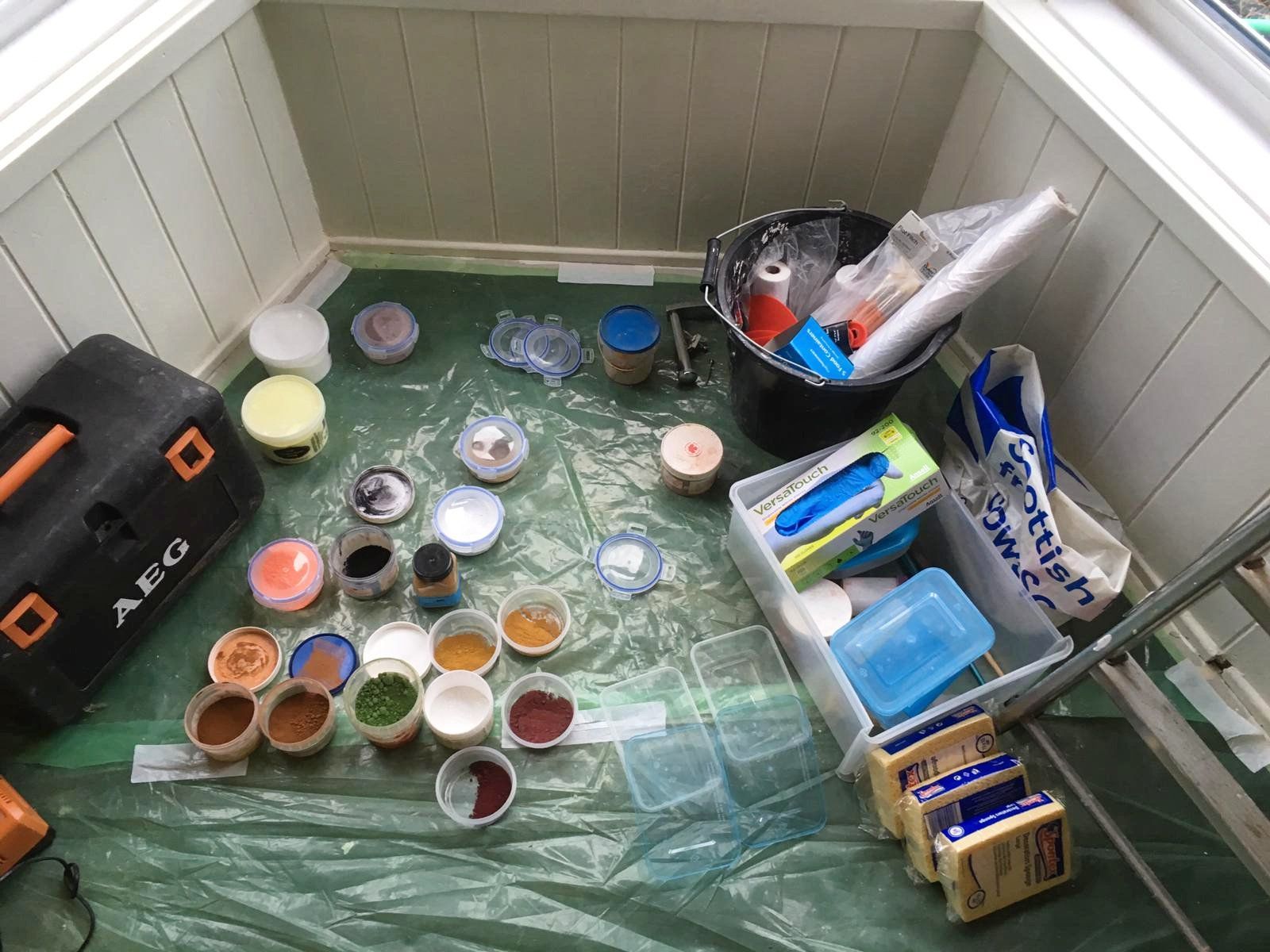 A toolbox is sitting on the floor next to a bunch of paint containers.