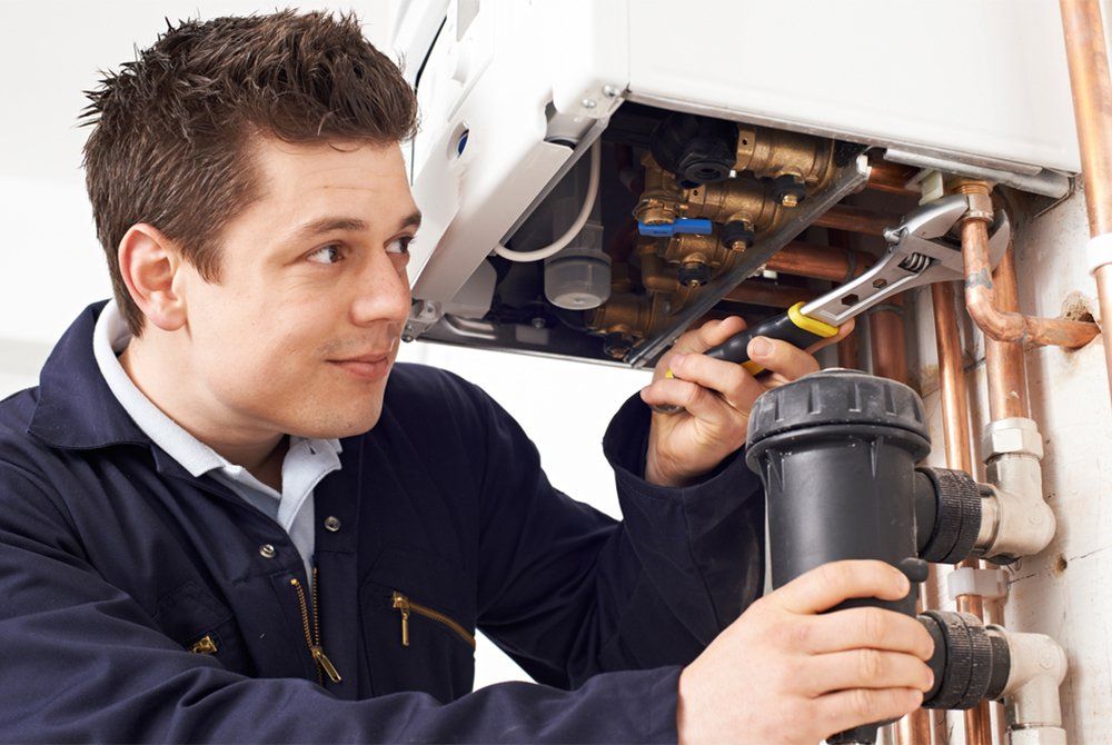 Male Plumber Working On Central Heating Boiler